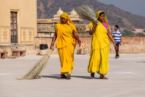 Women dressed in yellow sari cleaning the floor